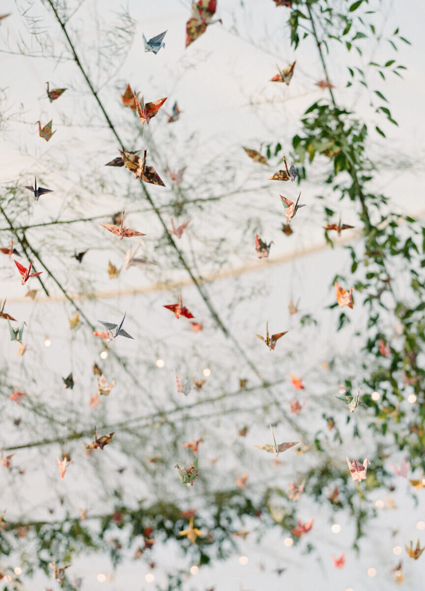 An installation of origami cranes and greenery hung over the dancefloor at this tented, waterfront wedding.
