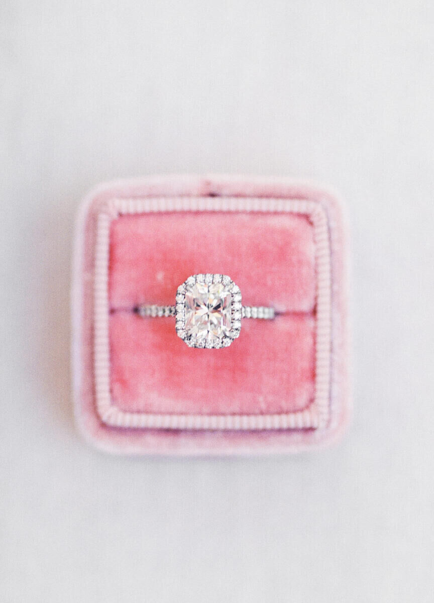 Wedding Ring Design: A radiant cut engagement ring with a halo setting sitting in a pink ring box.