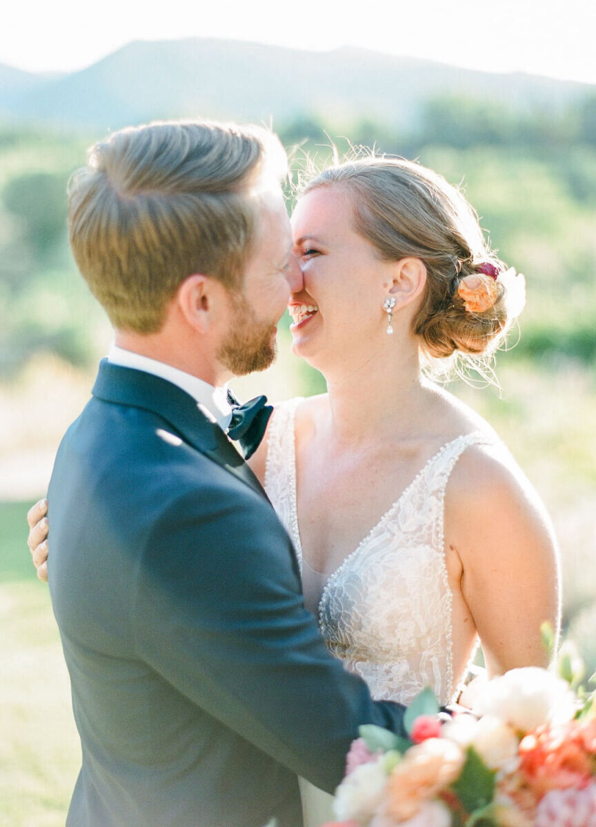 Wedding Tips: Bride and groom smiling, embracing, and leaning in about to kiss while standing outside.