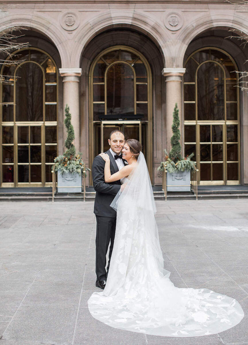 Wedding Tips: A laughing bride and groom standing close together outside of Lotte New York Palace.