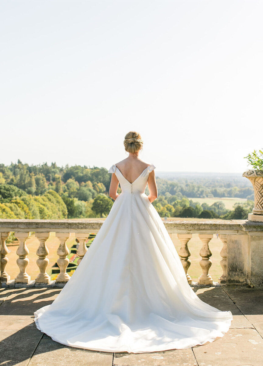 Wedding Tips: A bride standing outside looking at a countryside view from a grand terrace.