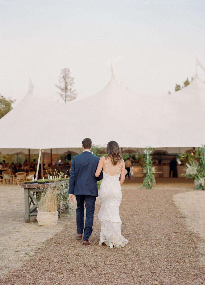 Wedding Tips: A bride and groom facing away from the camera and walking toward their wedding reception set-up.