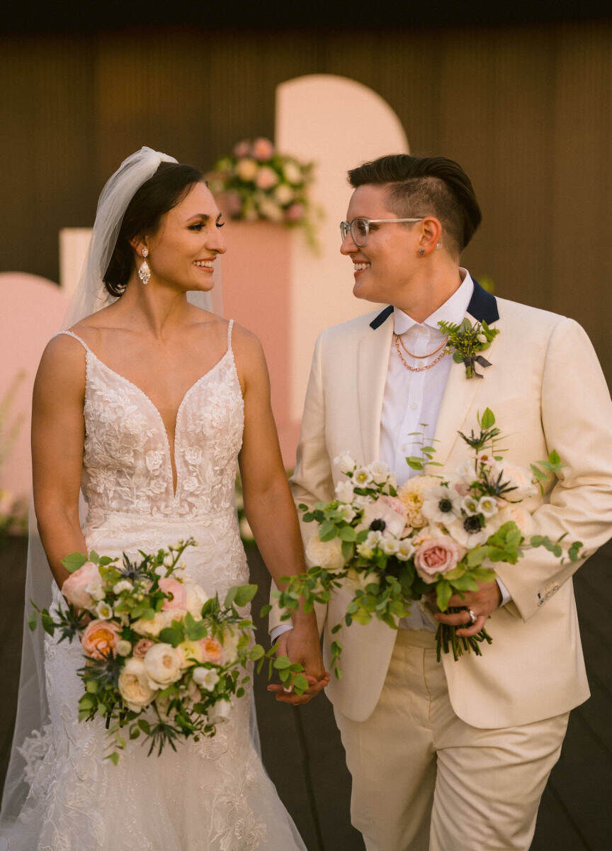 Wedding Tips: Two newlyweds holding hands, smiling, and looking at each other lovingly.