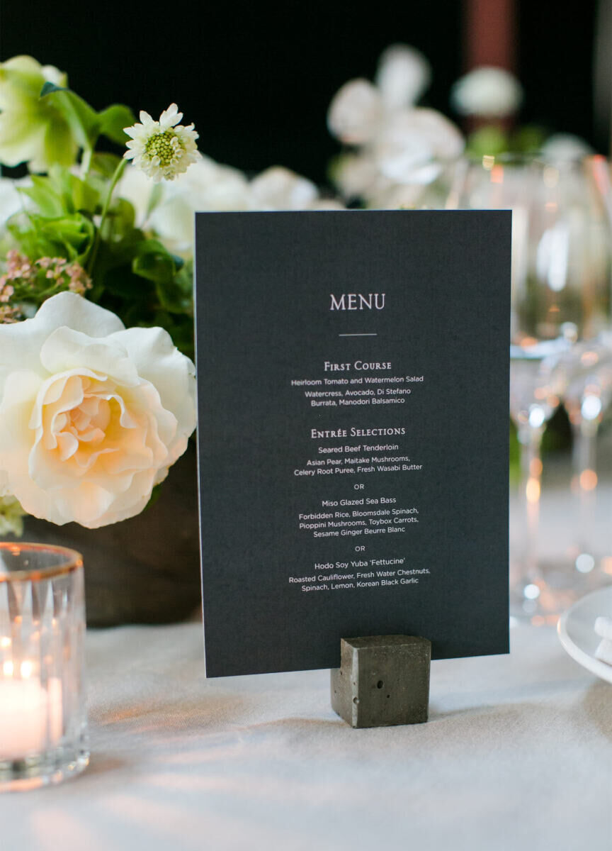 Wedding Tips: A menu on a stand listing a first course and three entree selections: seared beef tenderloin, miso glazed sea bass, or hodo soy yoba 