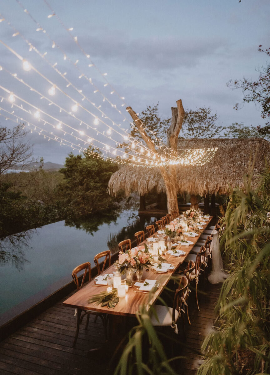 Wedding tips: A long reception table set-up, lit up by strings of delicate fairy lights above.