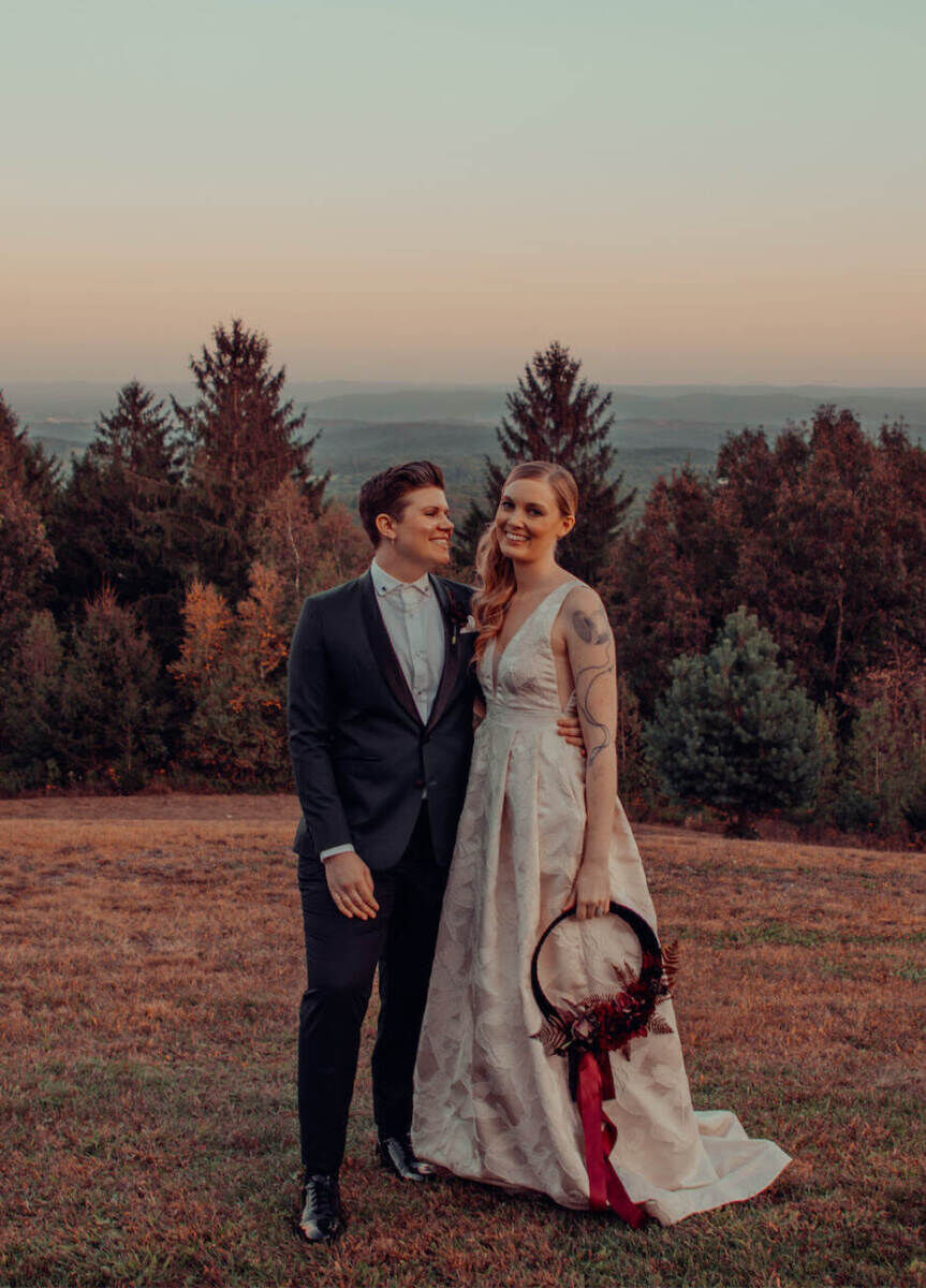 Wedding Tips: Two newlyweds standing close together in a field and smiling.