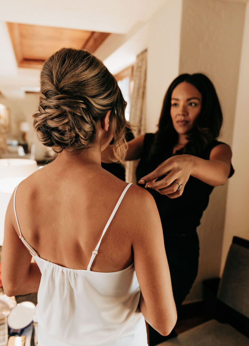 Wedding Tips: Stylist Ashley Smith looking at a bride's hair and reaching to adjust it with herhands.